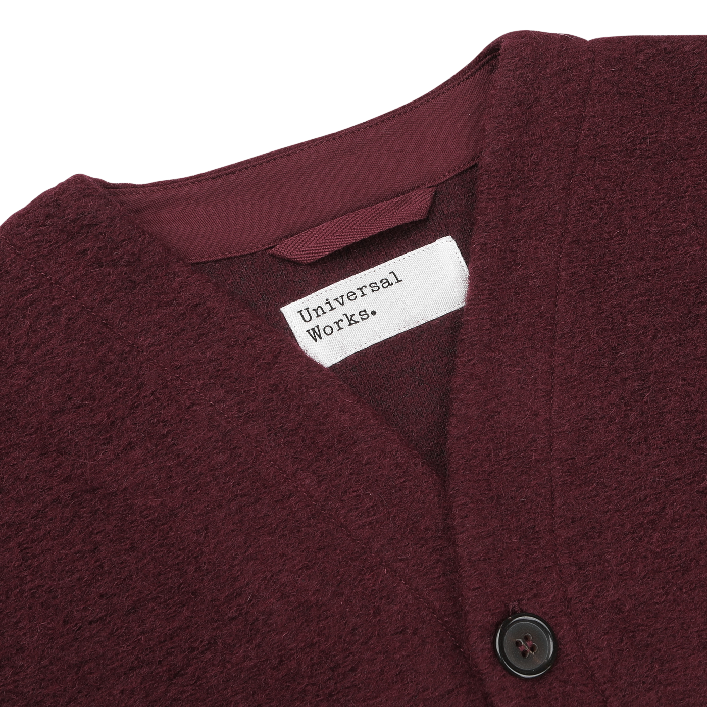 Close-up of the Deep Red Wool Fleece Cardigan with a V-neckline, featuring a white label reading "Universal Works" and black buttons.