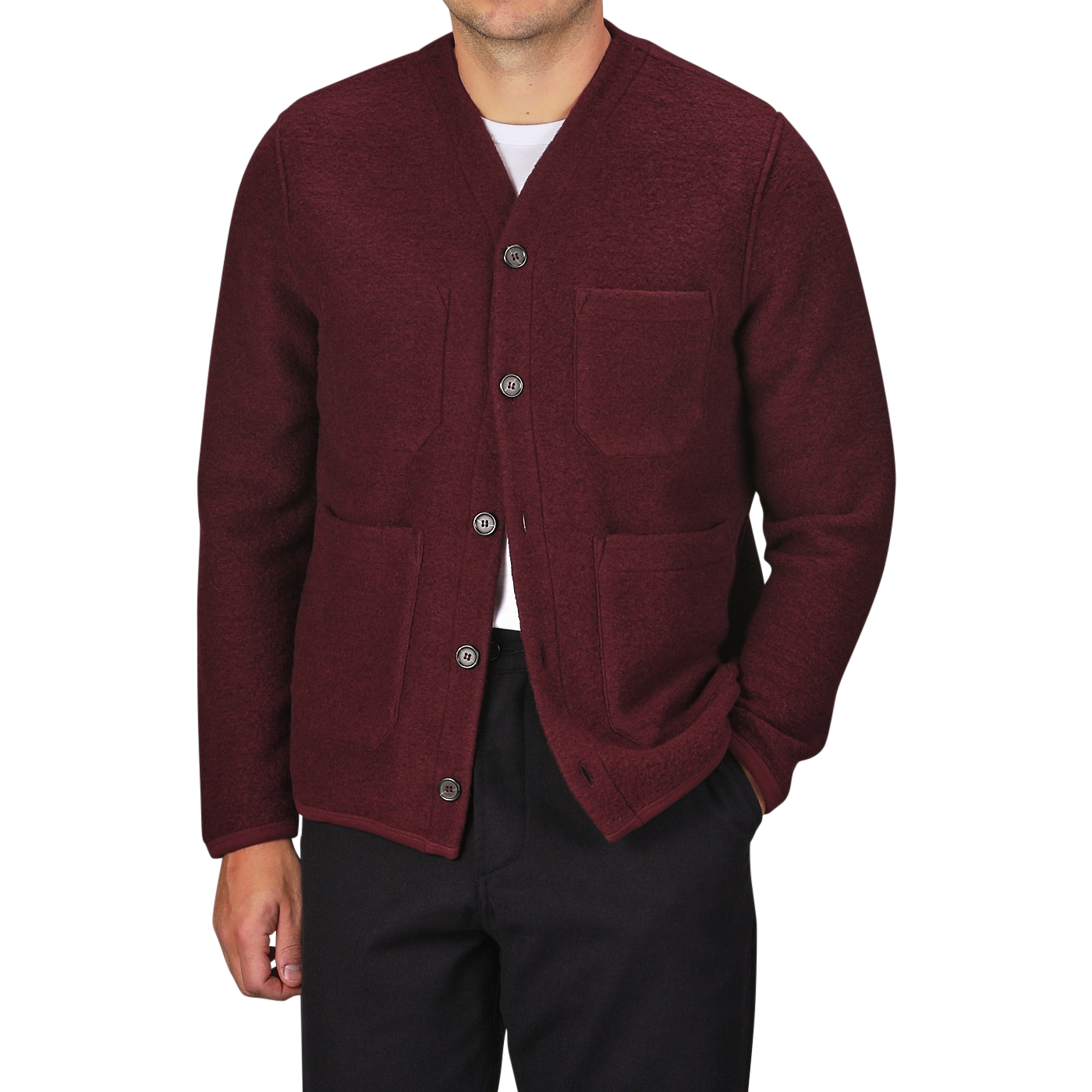 A person wearing the Deep Red Wool Fleece Cardigan by Universal Works over a white shirt, paired with black trousers. The stylish piece, featuring two front pockets, evokes the timeless elegance characteristic of Universal Works.