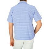 The back view of a man wearing a Light Blue Cotton Camp Collar Road Shirt by Universal Works.