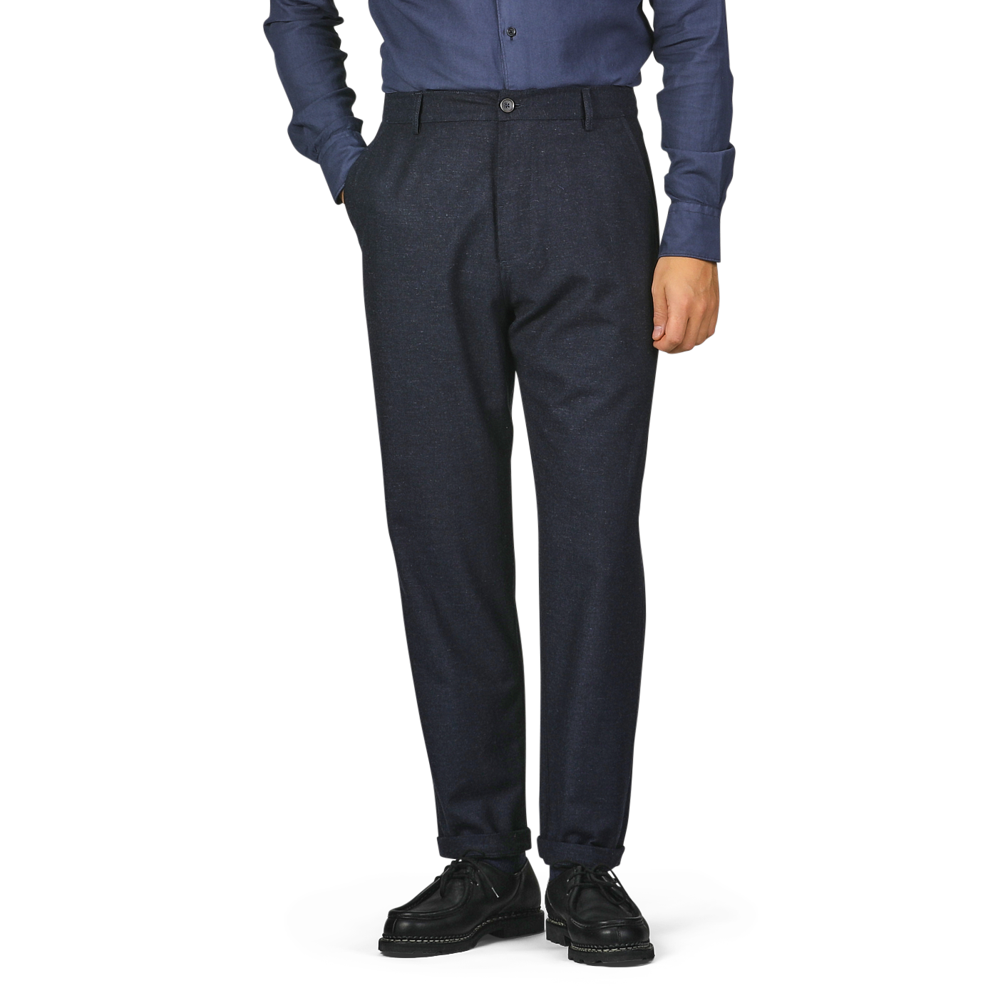 Person wearing a blue shirt, Universal Works Navy Blue Birdseye Tweed Military Chinos, and black shoes, standing with one hand in their pocket.