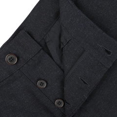 Close-up of navy blue Birdseye tweed Military Chinos from Universal Works, featuring a buttoned fly and part of the waist area. The fabric, made of upcycled wool tweed, is textured, with visible buttons and buttonholes.