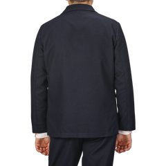 Back view of a person wearing a contemporary **Navy Blue Upcycled Tweed 2 Button Jacket** by **Universal Works** over a light-colored shirt, standing against a gray background.