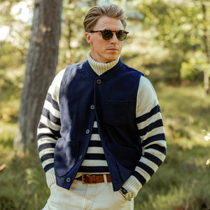 A man wearing a Universal Works Navy Blue Wool Blend Chore Waistcoat in the woods.