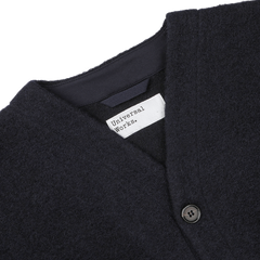 Close-up of a Navy Blue Wool Fleece Cardigan from Universal Works, showcasing its button and the white label near the neckline that reads "Universal Works.