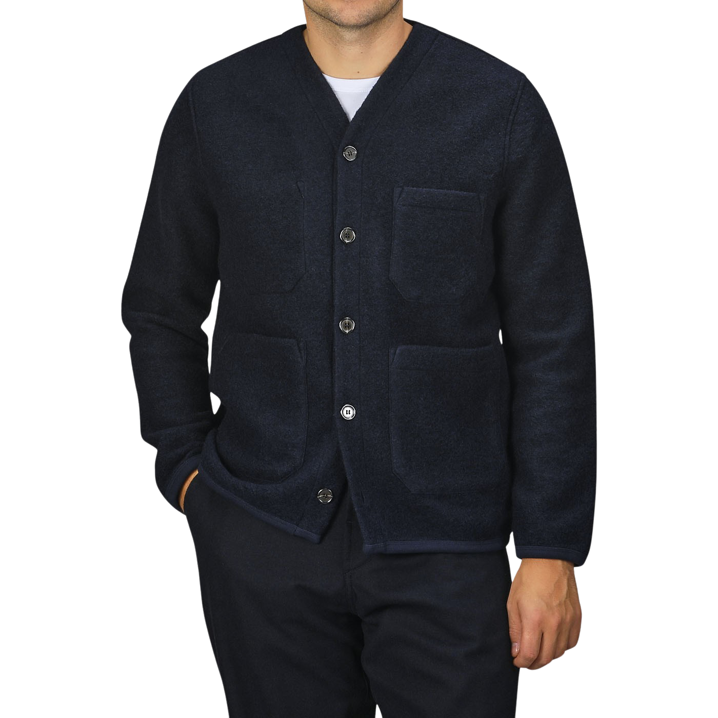 A person wearing a Navy Blue Wool Fleece Cardigan by Universal Works, featuring three pockets, stands against a plain background. They are also dressed in dark pants. Only the torso, part of the arms, and neck are visible.