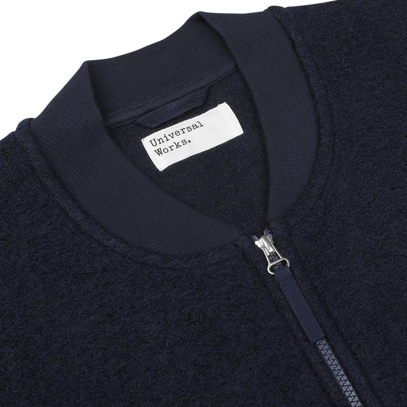 Close-up of the Navy Blue Wool Fleece Zip Waistcoat by Universal Works, featuring a front zipper and a white label.