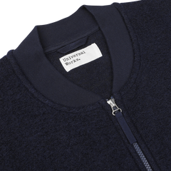 Close-up of the Navy Blue Wool Fleece Zip Waistcoat by Universal Works, featuring a front zipper and a white label.