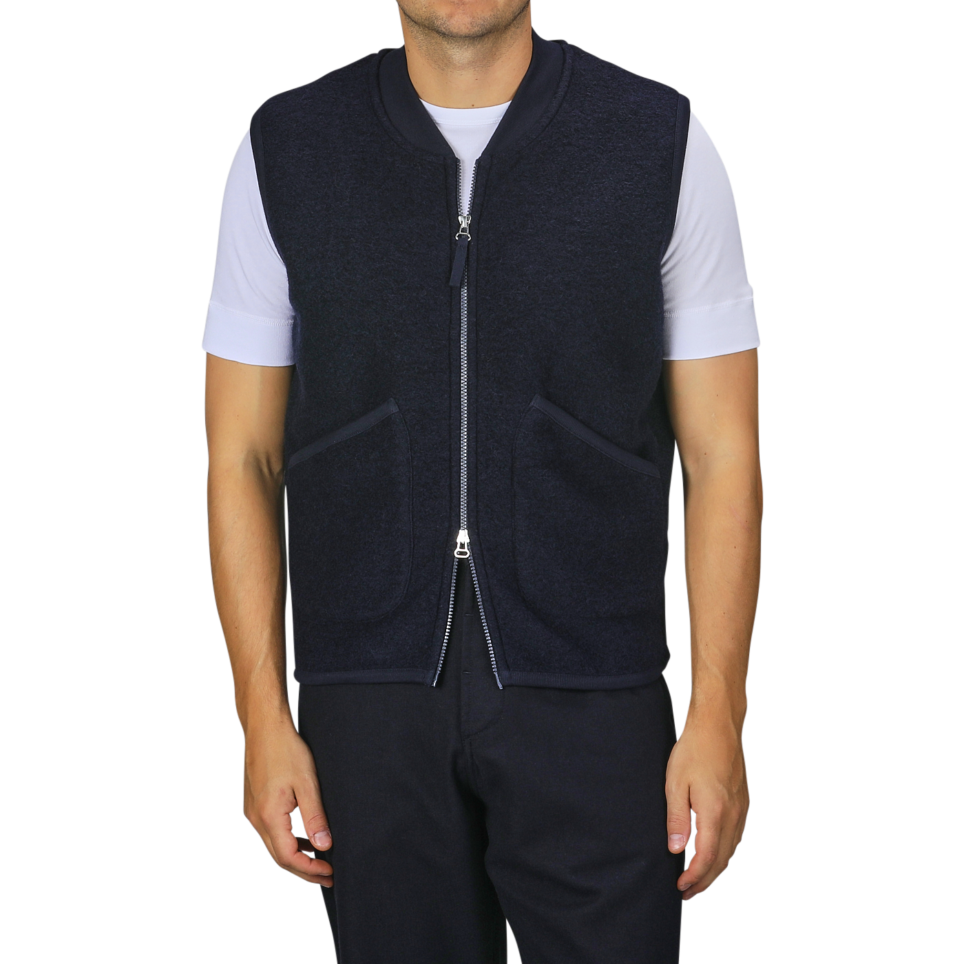 A person wearing a Universal Works Navy Blue Wool Fleece Zip Waistcoat over a white t-shirt and navy blue pants stands against a plain background.