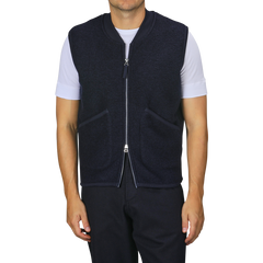 A person wearing a Universal Works Navy Blue Wool Fleece Zip Waistcoat over a white t-shirt and navy blue pants stands against a plain background.