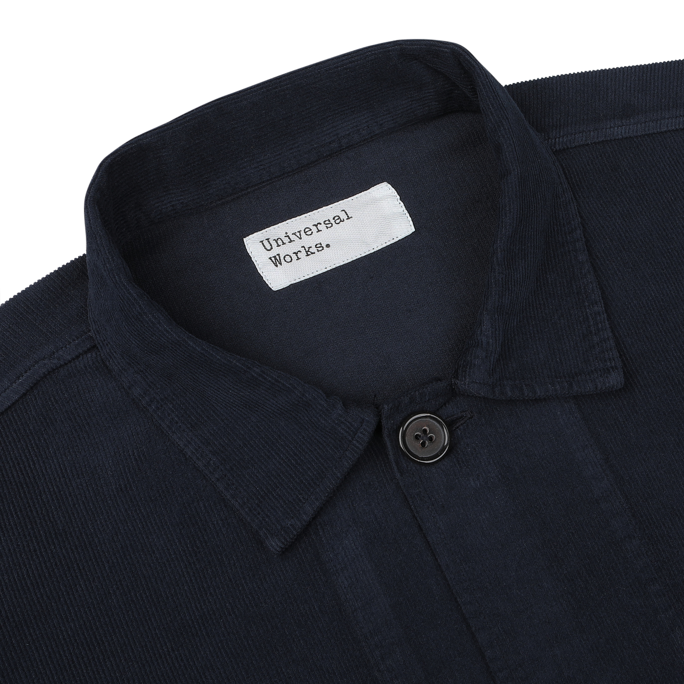 Close-up of a navy fine corduroy Bakers overshirt with a buttoned collar and a white label that reads "Universal Works.