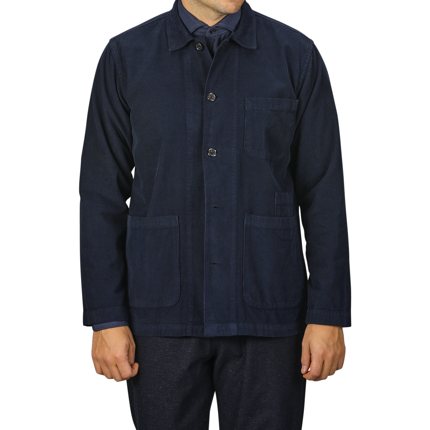 A person wearing the Universal Works Navy Fine Corduroy Bakers Overshirt, which is buttoned-up and features three pockets, paired with matching dark blue pants. The image is cropped at the neck and thighs.