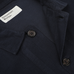 Close-up of a navy fine corduroy Bakers overshirt with a white tag that reads "Universal Works.