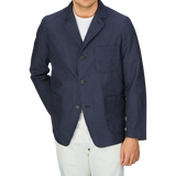 A man wearing a Universal Works Navy Puppytooth Linen Cotton 3-Button Jacket and white pants.