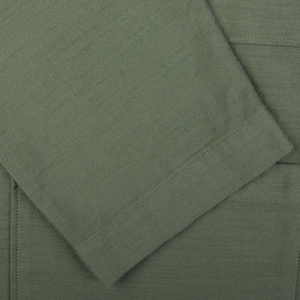 Close-up of olive green cotton sateen fabric with visible textures and seams from Universal Works Dockside Jacket.
