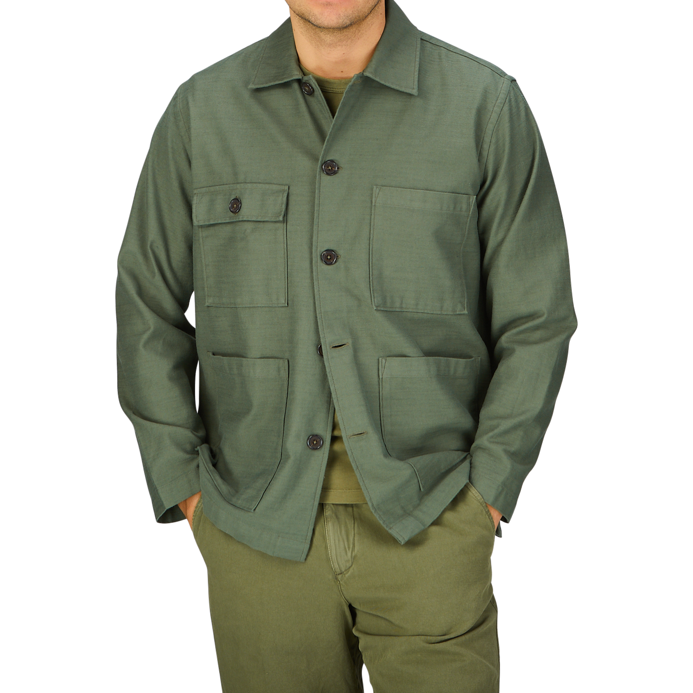 Man wearing a green Universal Works Olive Green Cotton Sateen Dockside Jacket with pockets standing against a gray background.