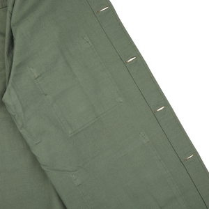Close-up of a green, Universal Works Olive Green Cotton Sateen Dockside Jacket with a focus on the pocket and button details.
