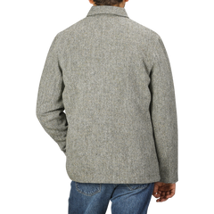 A person wearing an Olive Melange Harris Tweed Bakers C Jacket by Universal Works and blue jeans, viewed from the back against a plain background.