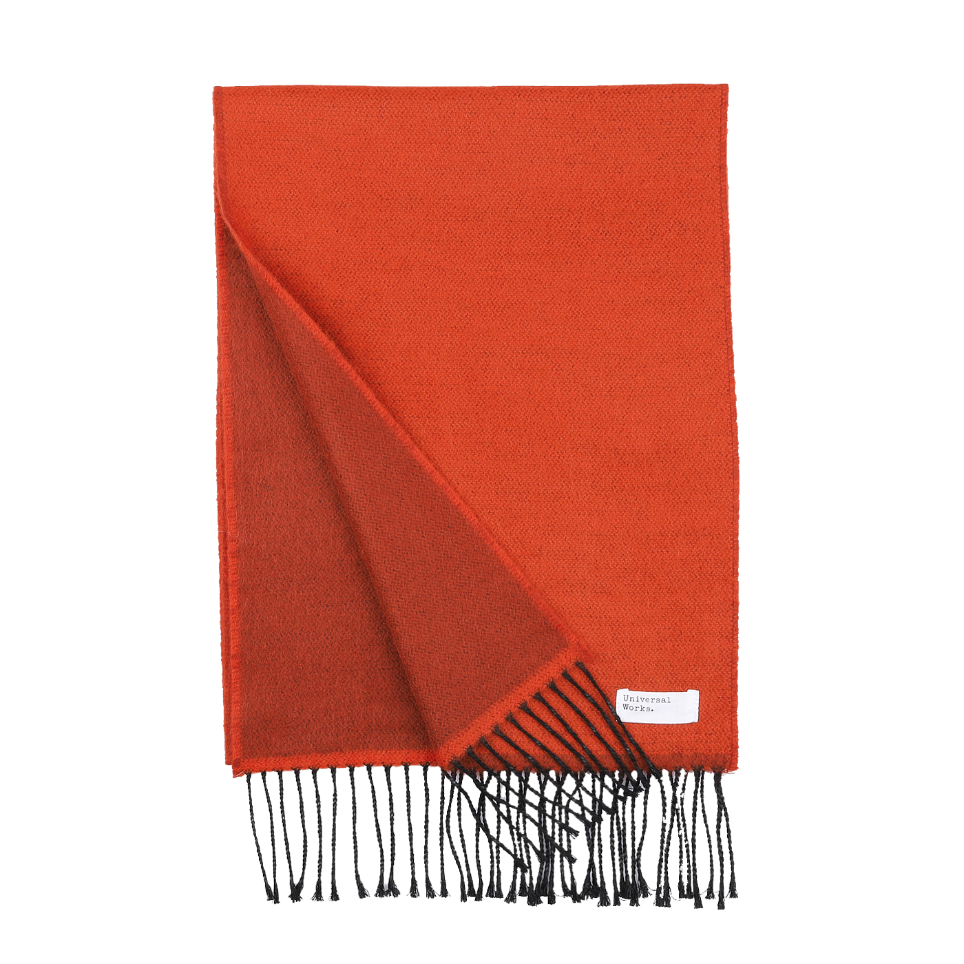 An orange double-sided acrylic scarf from Universal Works, featuring black fringe ends. A small white label with text is sewn onto one corner. Expertly made in Italy, this seasonal scarf ensures both quality and style.