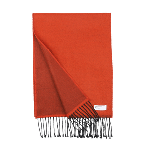 An orange double-sided acrylic scarf from Universal Works, featuring black fringe ends. A small white label with text is sewn onto one corner. Expertly made in Italy, this seasonal scarf ensures both quality and style.