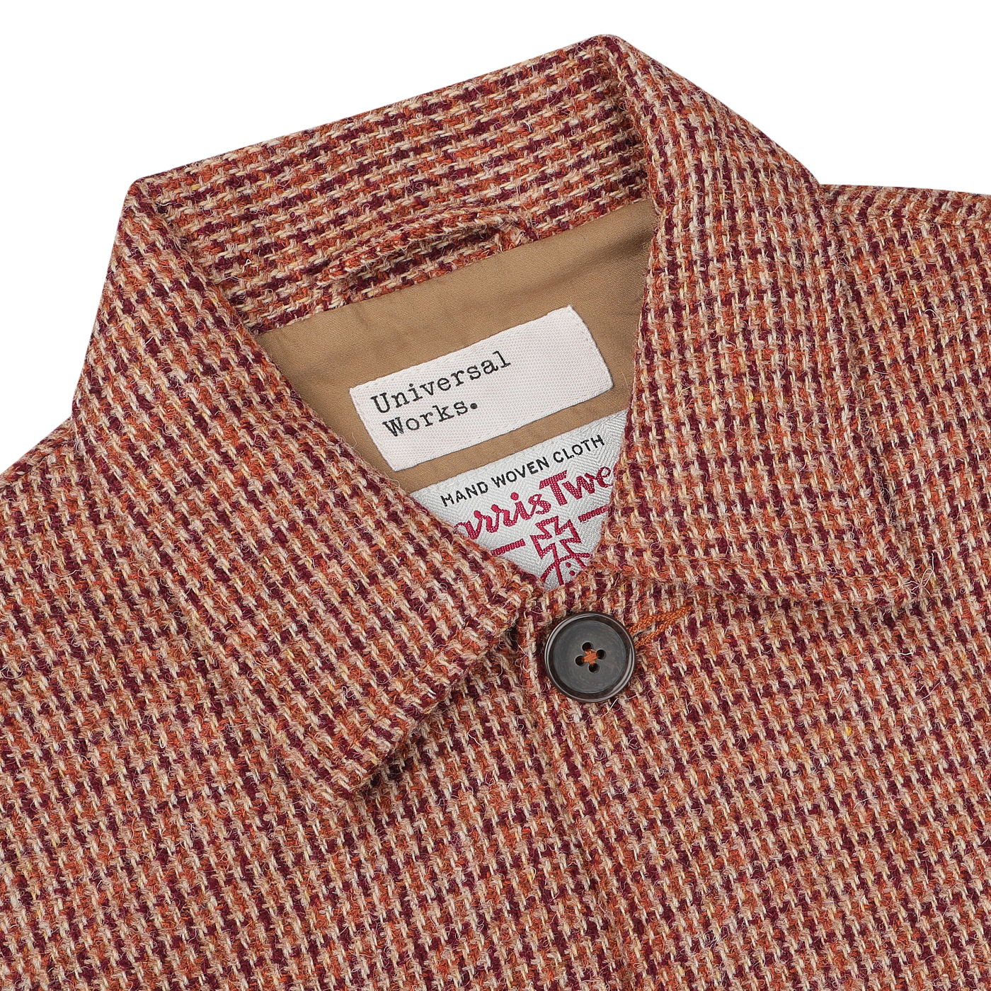 Close-up view of a Rust Orange Harris Tweed Bakers C Jacket with a label that reads "Universal Works." The chore jacket features a buttoned front.