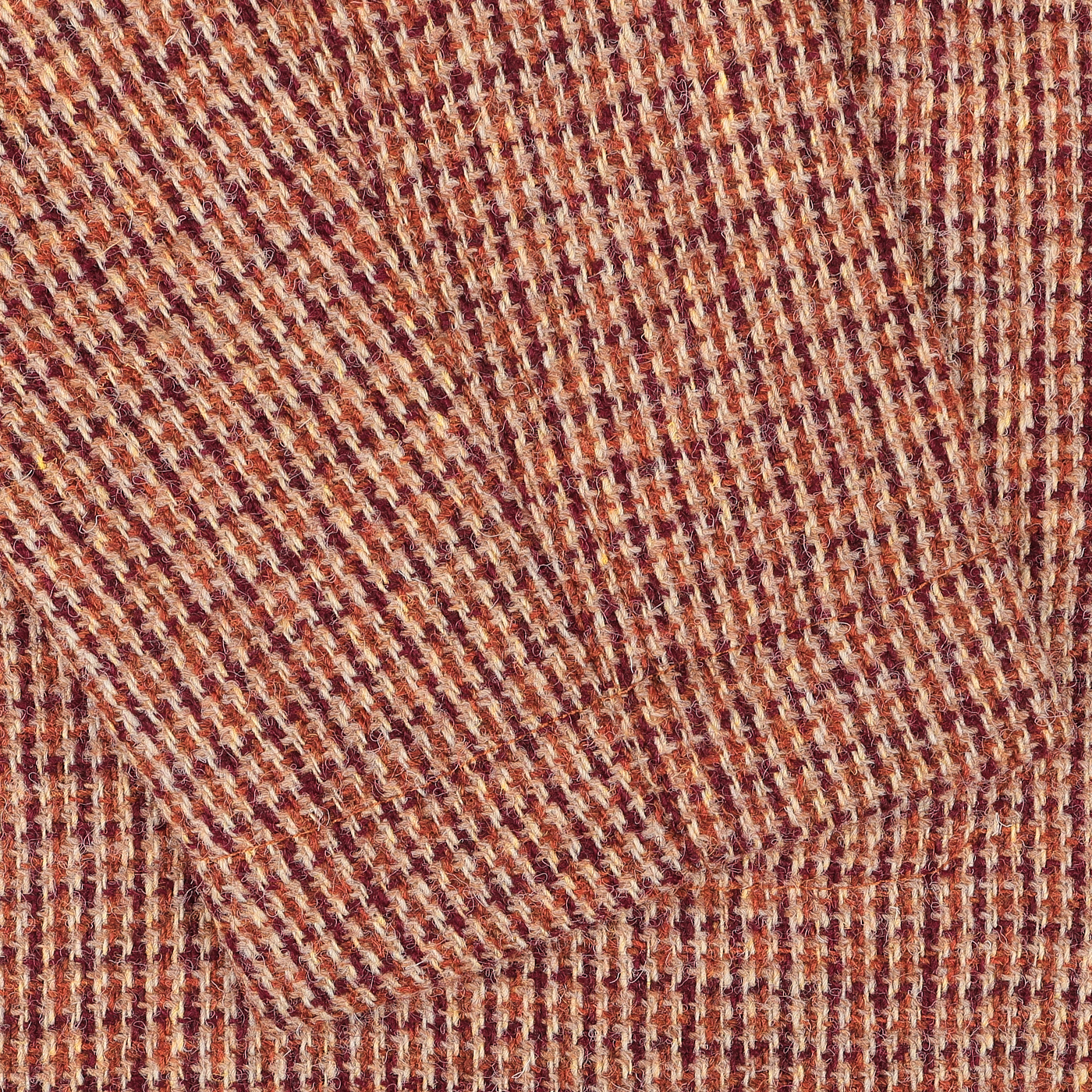 Close-up of a textured, woven Rust Orange Harris Tweed fabric with a plaid pattern featuring intersecting red, orange, and beige stripes, from the Bakers C Jacket by Universal Works.