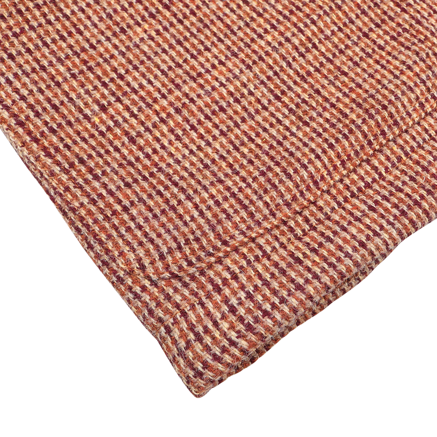 A close-up of the folded fabric from the Rust Orange Harris Tweed Bakers C Jacket by Universal Works, showcasing the intricate weave typical of Harris Tweed in shades of red, orange, and beige.