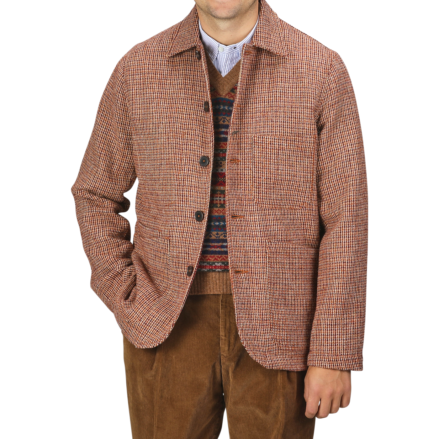 Person wearing a Rust Orange Harris Tweed Bakers C Jacket by Universal Works over a patterned sweater and brown pants, standing against a plain background.