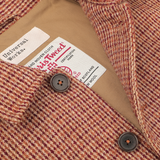 Close-up of a Rust Orange Harris Tweed Bakers C Jacket displaying two brown buttons and a label that reads "Universal Works." The label also provides certification details.