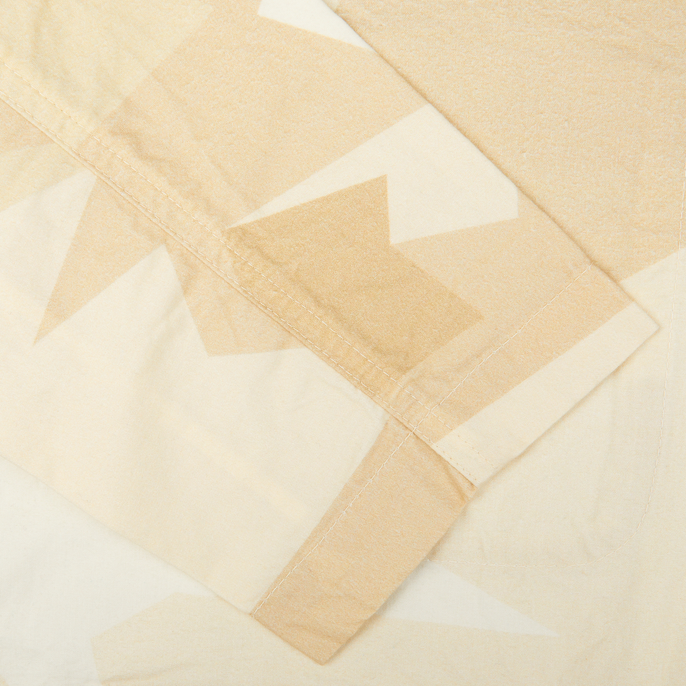 A close up of a sand beige camo cotton piece of fabric from Universal Works Bakers Jacket.