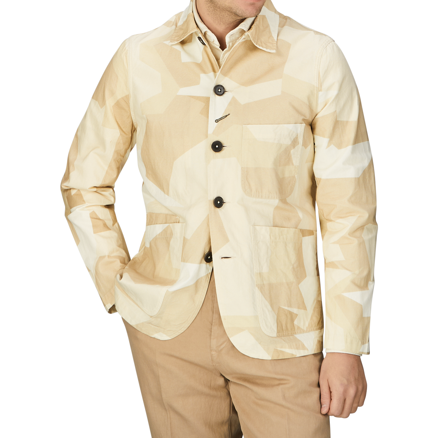 A man wearing a sand beige camo cotton Universal Works bakers jacket and tan pants.