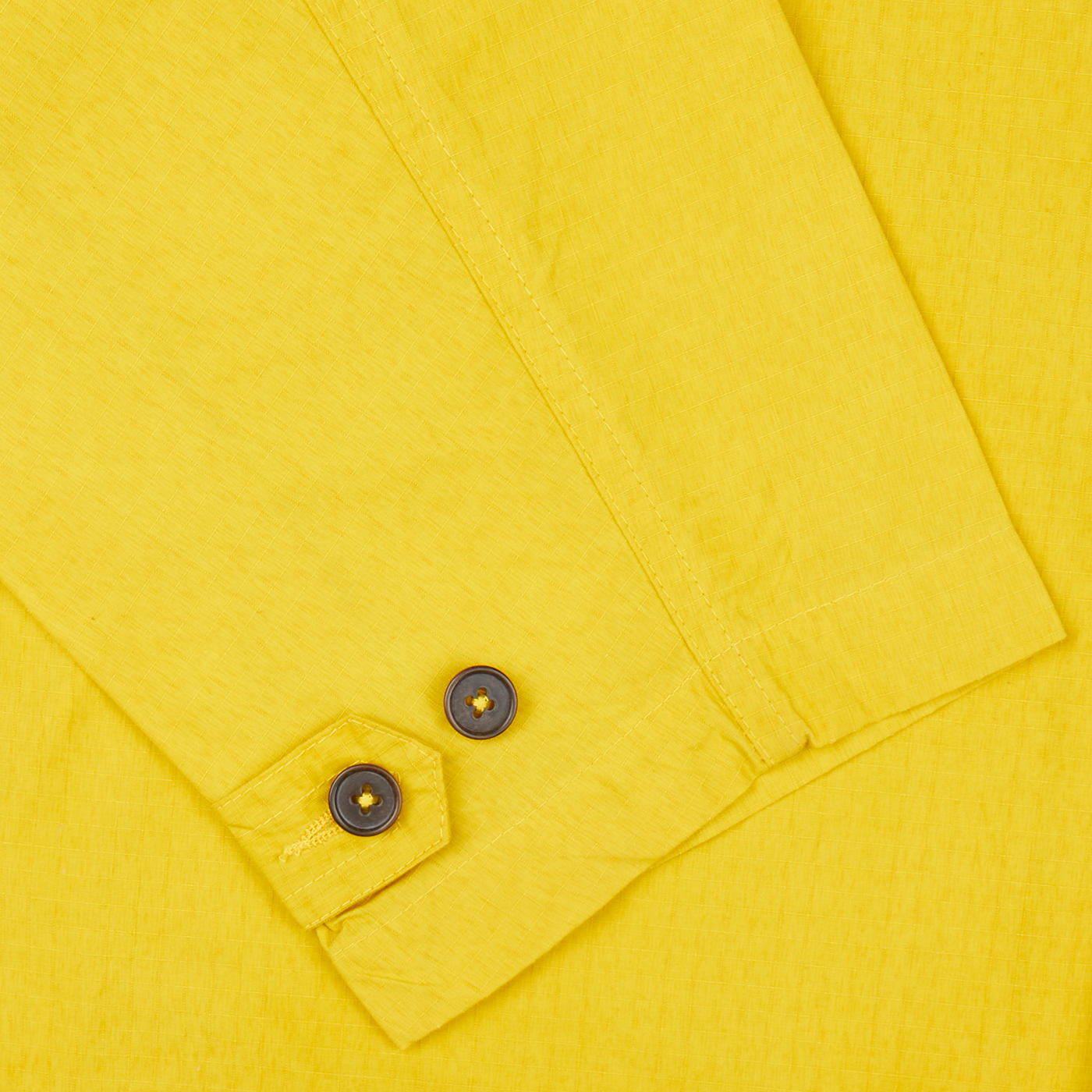 A close up of a yellow Universal Works Yellow Cotton Ripstop Stanedge Jacket with buttons.