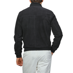 A man in a stylish Valstar Navy Blue Suede Leather Valstarino Jacket, paired with white pants, is seen from the back.