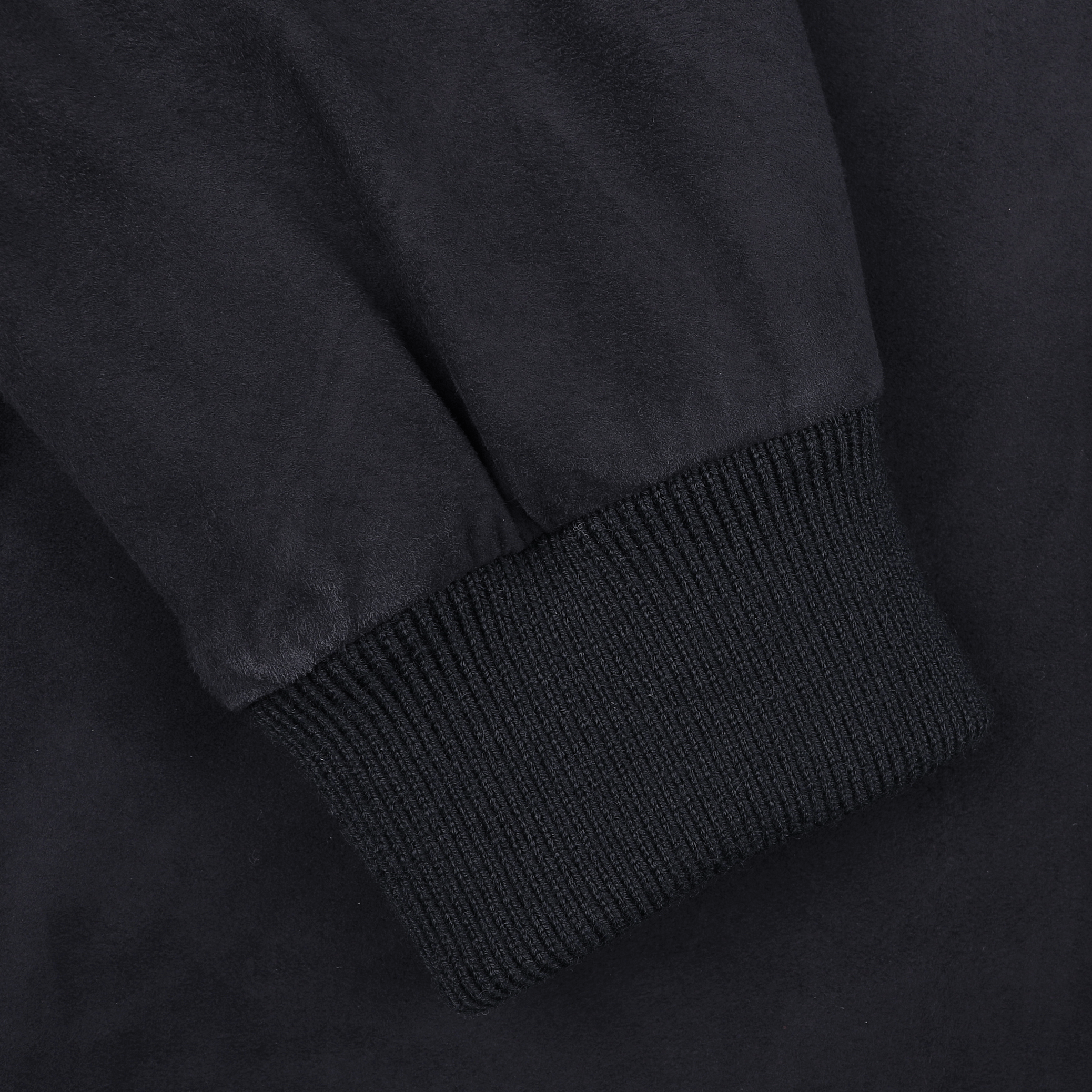 Close-up of a navy blue suede leather Valstarino jacket sleeve by Valstar, featuring a ribbed cuff reminiscent of the classic A-1 pilot jacket, set against a dark background.