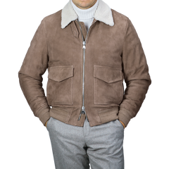 Wearing a Taupe Suede Leather Shearling Flight Jacket from Valstar over a white turtleneck, paired with gray pants.