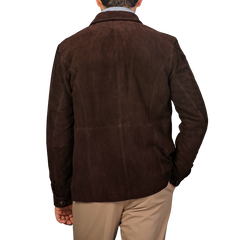 A person wearing a Werner Christ Dark Brown Suede Leather Amaro Shirt Jacket and beige pants faces away from the camera against a plain gray background.