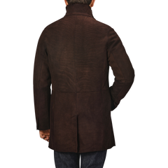 A person wearing a dark brown suede leather Blake coat by Werner Christ, viewed from the back with one hand in their pocket.