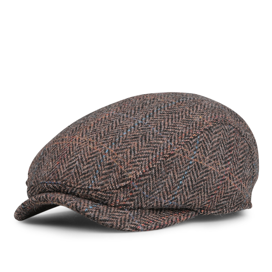 The Wigéns Dark Brown Ivy Contemporary Harris Tweed Cap is crafted from dark brown fabric with a herringbone pattern, featuring subtle blue and red accents against a white background.