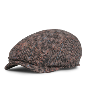 The Wigéns Dark Brown Ivy Contemporary Harris Tweed Cap is crafted from dark brown fabric with a herringbone pattern, featuring subtle blue and red accents against a white background.