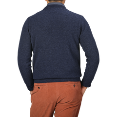 A person wearing an Astra Blue Crew Neck Lambswool Sweater by William Lockie and brown pants is shown from the back against a gray background.