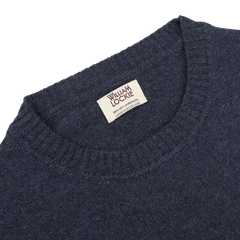 A close-up of an Astra Blue Crew Neck Lambswool Sweater featuring a clothing label that reads "William Lockie, 100% Lambswool, Made in Scotland.