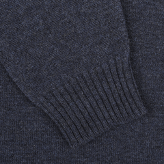 Close-up of a navy blue knitted fabric, focusing on the ribbed cuff of a sleeve. The texture of the material is clearly visible, showcasing its weave and color. This intricate craftsmanship could only be from an Astra Blue Crew Neck Lambswool Sweater by William Lockie.