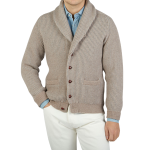 A man wearing a Beige Grey Plaited Lambswool Shawl Collar Cardigan by William Lockie and white pants made of Scottish lambswool.
