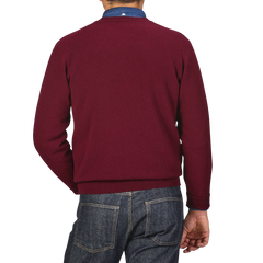 A person is seen from behind wearing a William Lockie Bordeaux Deep V-Neck Lambswool Sweater and blue jeans.