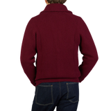 The back view of a man wearing a maroon William Lockie Bordeaux Lambswool Shawl Collar Cardigan.