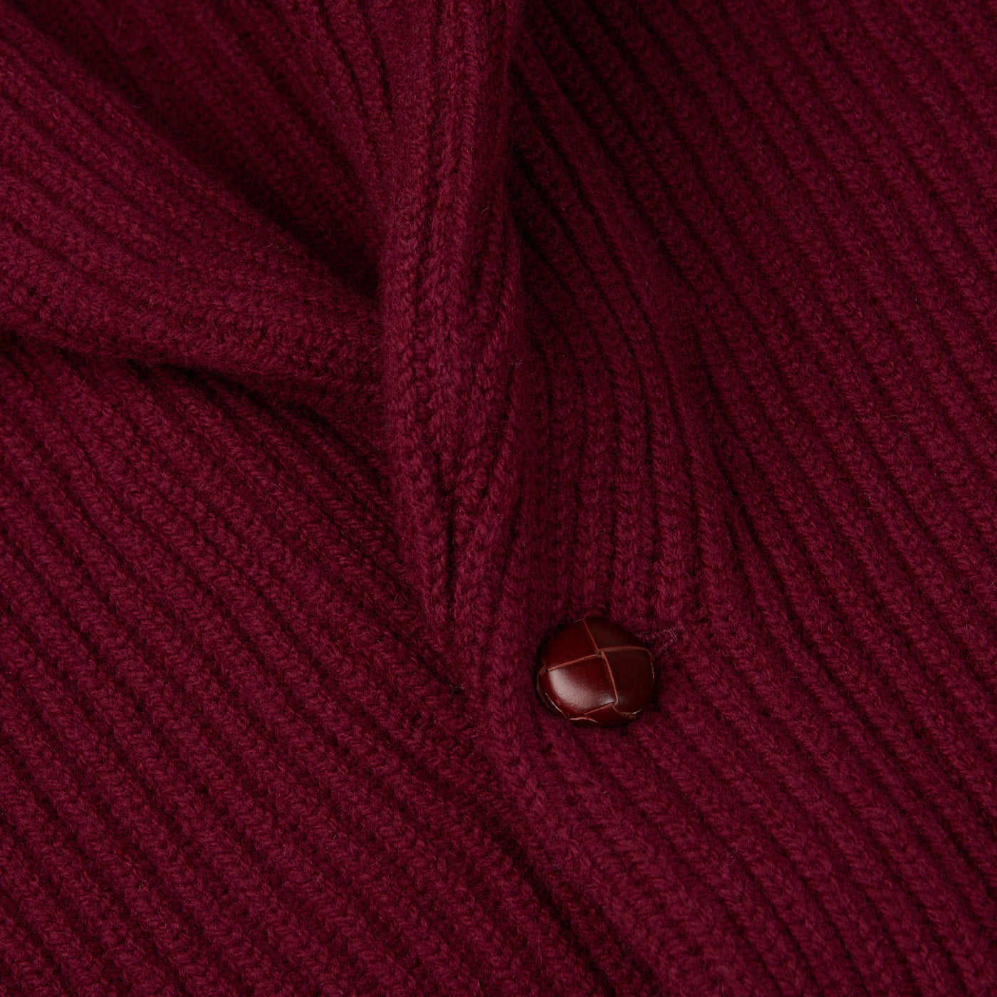 A close up of a William Lockie Bordeaux Lambswool Shawl Collar Cardigan with leather buttons.