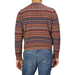 A man is pictured from the back against a plain background, wearing a William Lockie Brown Fair Isle Crew Neck Lambswool Sweater with red, blue, and brown stripes, paired with blue jeans.