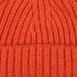 A close up image of a William Lockie Burnt Orange Cashmere Ribbed Short Beanie.