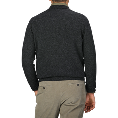 A person clad in a William Lockie Charcoal Grey Crew Neck Lambswool Sweater paired with light grey pants is shown from the back against a plain grey background, embodying a smart casual look.