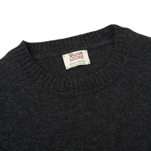A William Lockie Charcoal Grey Crew Neck Lambswool Sweater, with a label on it.
