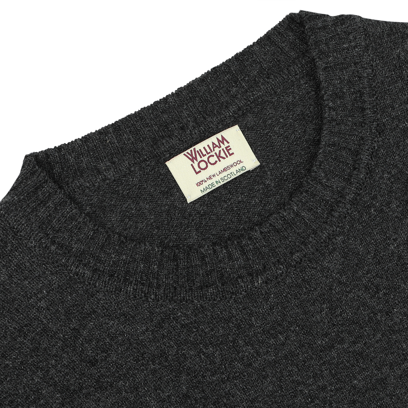 A Charcoal Grey Crew Neck Lambswool Sweater by William Lockie, featuring a label that reads "William Lockie, Dry Clean, Made in Scotland," crafted from exquisite Scottish lambswool for a smart casual look.